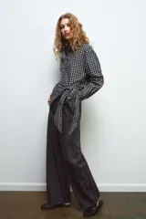 Camisa oversize de algodón con estampado de cuadros, cuello solapa, manga larga con puños y cierre frontal con botones. Presenta un detalle de pañuelo integrado en el mismo tejido que se anuda en la parte frontal.