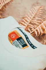 Buzo color crudo con cuello redondo y puños y cintura acanalados. Estampado en la espalda con diseño de palmera y texto enmarcado en damero.