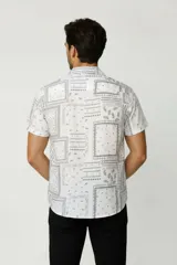Camisa de manga corta color blanco con estampado tipo bandana en tonos grises, de corte holgado, con cuello camisero y cierre frontal de botones.