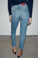 Jeans mom fit de tiro alto color negro con efecto lavado, diseño de cinco bolsillos y corte tobillero.