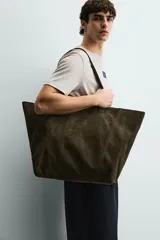 Bolso tipo shopper de piel con acabado serraje, color verde militar. Cuenta con dos asas de mano y un bolsillo interior con cierre de cremallera.