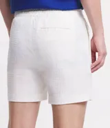 Bermuda de hombre, corte slim, color blanco con textura visible. Confeccionada principalmente en lino y algodón, con un pequeño porcentaje de elastano para mayor ajuste. Presenta cintura elástica y bolsillos laterales.