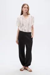Pantalón de poliéster color negro, de tiro alto y corte holgado con frunces en los tobillos.