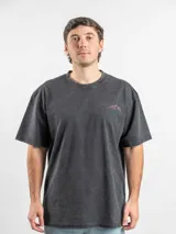 Remera oversize de algodón color negro con efecto lavado. Presenta un estampado gráfico en la espalda con la frase 'Freeze the moment' y un diseño de cámara fotográfica en tonos rojizos.