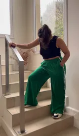 Pantalón de jogging verde de plush con elástico en la cintura, bolsillos y cinta con el logo a lo largo de la pierna.