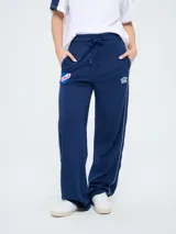 Pantalón de jogging azul marino con cordón ajustable en la cintura, bolsillos laterales y líneas blancas laterales. Presenta el escudo del Club Nacional de Football y el logo de Umbro bordados.