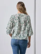 Blusa de gasa con estampado geométrico en tonos negro, gris y celeste. Tiene cuello redondo y mangas 3/4 amplias con abertura y botón.