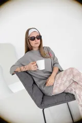 Pantalón acampanado de encaje negro, con estampado de pequeñas flores en relieve. El tejido es semitransparente y cae sobre un calzado tipo zueco negro.