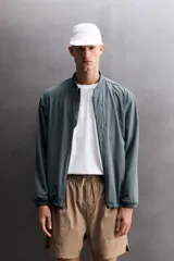 Chaqueta técnica de corte relajado, confeccionada en tejido compacto y elástico. Presenta cuello y puños acabados en rib, cierre frontal con cremallera, bolsillos frontales con cremallera oculta y bajo ajustable con elástico en los laterales.