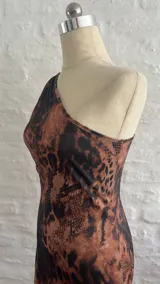 Vestido corto ajustado al cuerpo, con un solo hombro y estampado animal print en tonos marrones y negros.