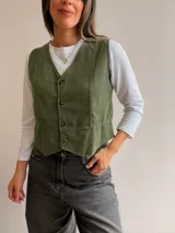 Chaleco de pana fina color marrón oscuro, con escote en V, cierre frontal de botones y corte entallado.