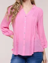 Blusa de silueta suelta color azul, con escote en V y cuello mao. Cuenta con abotonadura frontal, alforzas verticales en el pecho y mangas tres cuartos con puños elastizados.