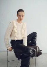 Sweater de punto color crudo, con cuello redondo y volados aplicados en los hombros.