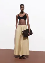 Falda larga de corte evasé en color beige, confeccionada en mezcla de algodón y poliamida. Presenta cintura con elástico, tiro bajo y bolsillos laterales.