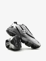 Zapatillas New Balance modelo M1000EGR, color plata y negro, con capellada de malla y revestimientos sintéticos. Cuentan con amortiguación ABZORB en el talón, Stability Web en el antepié, detalles reflectantes y logo 'N' engomado con contorno transparente.