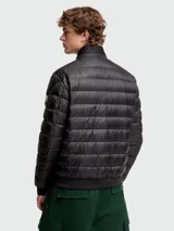 Campera corta de plumas Moncler modelo Rigel, color negro, con diseño acolchado horizontal, cuello alto con cierre de broches y cierre frontal completo.