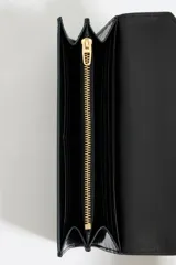 Billetera negra charolada con cierre de solapa y logo dorado de la marca Bimba y Lola.