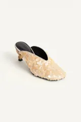 Zapato de tacón destalonado estilo mule, totalmente revestido de abalorios y lentejuelas en tonos claros, con escote en pico, punta cuadrada y tacón medio metalizado.