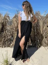 Vestido largo de corte evasé, con cuerpo superior blanco con volados en los hombros y falda negra con botones frontales.