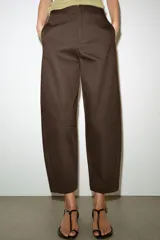 Pantalón de tiro medio con diseño barrel, pernera holgada que se estrecha hacia el tobillo, bolsillos delanteros y bolsillos de plastrón en la espalda. Confeccionado en tejido con textura de espiga, cuenta con cierre frontal de cremallera, botón interior y gancho.