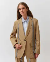 Blazer de algodón color tostado con cierre de un botón, solapas clásicas y bolsillos con solapa. Presenta detalles de bandas rayadas verticales a lo largo del frente, mangas y espalda.