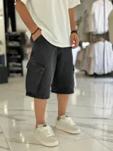 Bermuda de jean estilo cargo con bolsillos laterales con solapa, corte super baggy y lavado efecto desgastado.