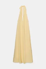 Vestido midi de tejido fluido color amarillo pálido, con cuello halter que se anuda en la parte superior y escote pronunciado en pico.