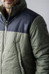 Campera puffer azul marino con canesú azul más claro en la parte superior y capucha. Cierre frontal con cremallera y bolsillos laterales.