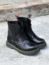 Bota negra de cuero charol con cordones, suela track color caramelo y tirador trasero.