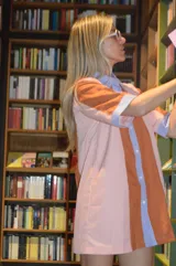 Camisola corta con cuello camisero y mangas cortas, con diseño a rayas verticales en tonos naranja, rosa y celeste.