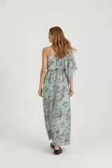 Vestido largo de diseño asimétrico con un solo hombro, confeccionado en tela fluida con estampado abstracto en tonos verdes y azulados. Presenta una manga tipo capa y corte holgado con elástico en la cintura.