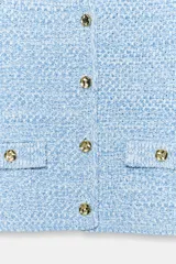 Chaqueta de punto en tono celeste, de cuello redondo, manga francesa y cierre frontal con botones dorados. Cuenta con bolsillos simulados con solapa y botones dorados en la parte delantera.