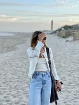 Saco de punto fino color beige, con mangas largas y cierre frontal mediante lazo anudado en el cuello. Diseño entallado y versátil.