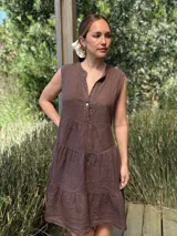 Vestido celeste de lino, sin mangas, con cuello mao y botones de nácar. Presenta varios cortes en su largo, aportando movimiento y un toque moderno a este diseño fresco y elegante.