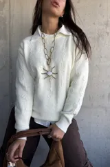 Sweater de punto color natural con diseño de flores bordadas en relieve, cuello redondo y puños acanalados. Presenta un corte clásico y versátil.