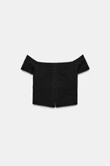 Top corto negro de punto con escote recto, hombros descubiertos, mangas cortas y cierre frontal con corchetes metálicos.