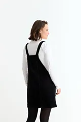 Jumper corto de pana negra con tirantes ajustables, bolsillos frontales y corte recto.