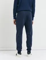 Pantalón jogging de tejido circular con cintura elástica y cordón ajustable. Presenta puños elastizados en el ruedo y bolsillos laterales.