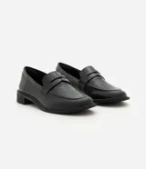 Mocasín Satinato de mujer confeccionado en cuero negro con acabado liso, puntera redondeada, costuras visibles, tira decorativa en la pala y suela con taco bajo.