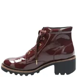 Bota acordonada de estilo urbano en acabado charol color bordó. Presenta una suela de goma robusta con plataforma y un taco cuadrado de altura media. Incluye ojales metálicos dorados y cordones al tono.