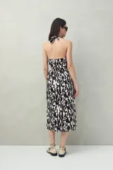 Vestido midi con estampado abstracto en blanco y negro, escote halter y falda acampanada con abertura frontal.
