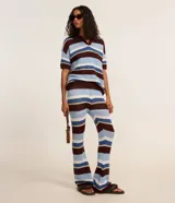 Pantalón femenino de punto con efecto crochet, de corte flare, cintura elástica y rayas horizontales en diferentes anchos y colores (azul claro, azul medio, bordó y blanco).