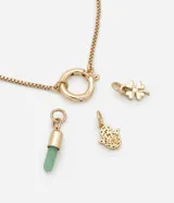 Pulsera de cadena ajustable en tono dorado con tres dijes colgantes: una mano de Fátima, un dije cilíndrico con piedra natural verde y un trébol de cuatro hojas.