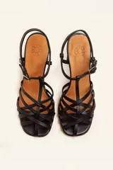 Sandalia de cuero negro con tiras cruzadas en el empeine, diseño en T con tira ajustable al tobillo y taco cuadrado.