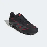 Championes de fútbol Adidas Predator Club, color negro con detalles en rojo y gris. Cuentan con una parte superior sintética con textura Strikeprint para mayor agarre y control del balón, lengüeta perforada para ventilación y suela versátil apta para terreno firme y césped artificial.