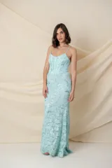 Vestido largo de fiesta color celeste agua marina, con breteles finos, corsé armado y falda con cola de sirena. El vestido está confeccionado en encaje bordado con lentejuelas plateadas.