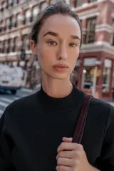 Vestido corto negro de tejido de punto, con cuello redondo alto y mangas anchas a la altura del codo. Presenta un corte entallado en la cintura y cierre con cremallera oculta en la espalda.