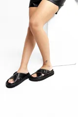 Sandalias de cuero blancas con suela negra, tiras cruzadas y hebillas ajustables.