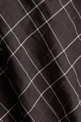 Blusa de manga larga con estampado a cuadros en tonos oscuros (negro/marrón y blanco). Presenta cuello drapeado con tira para atar en la nuca, hombros caídos y cintura entallada con pinzas moldeadoras.