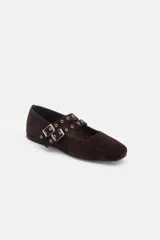 Ballerina de gamuza color marrón oscuro, con diseño de doble tira con hebillas metálicas y ojales decorativos sobre el empeine.